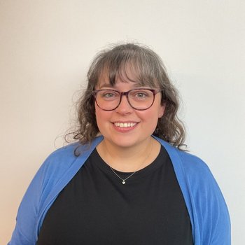 Women smiling with glasses and a blue cardigan.