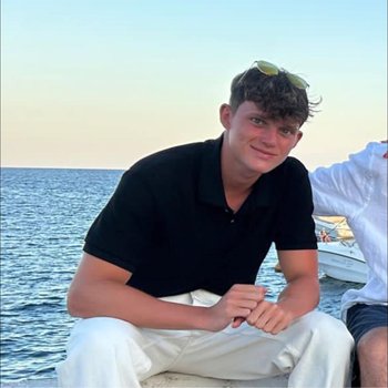 Boy sitting by the beach on a rock.
