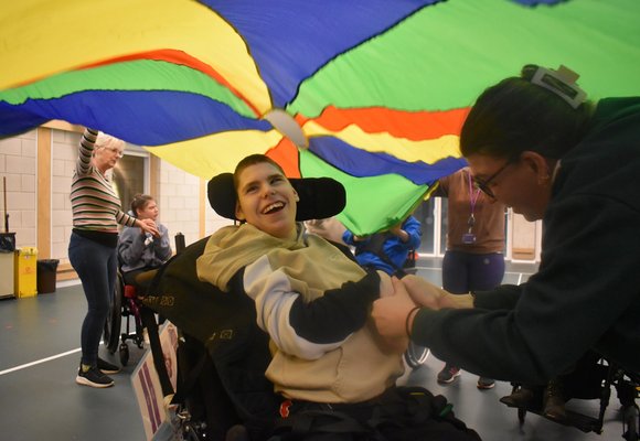 Boy in wheelchair smiling under a colourful parachute 