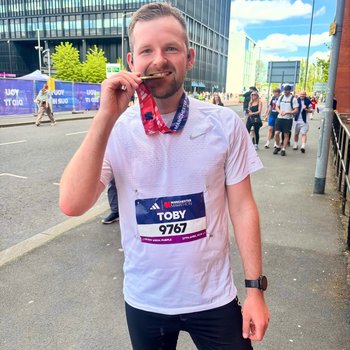 Man smiling with a marathon medal.