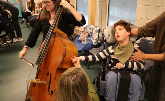 Boy feeling the vibrations from a cello.