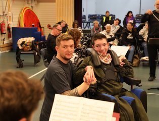 Boy smiling at someone playing an instrument.