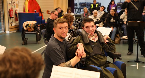 Boy smiling at someone playing an instrument.