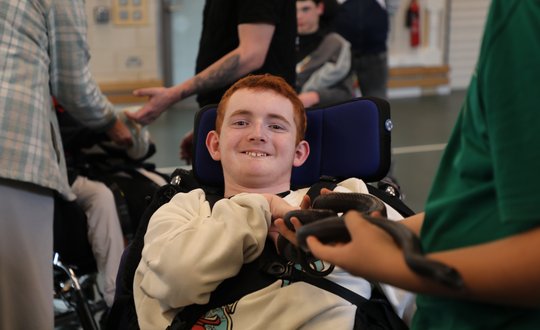 Boy smiling at a black snake.