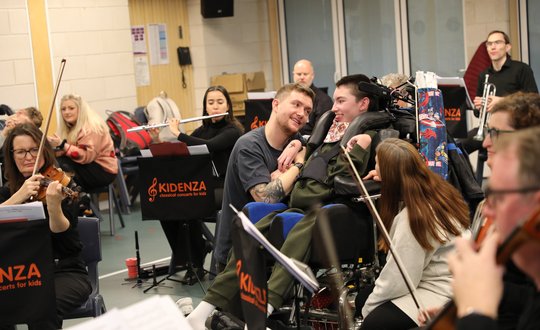 Boy in the middle of an orchestra.