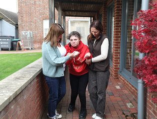 Girl walking with the help from two women.