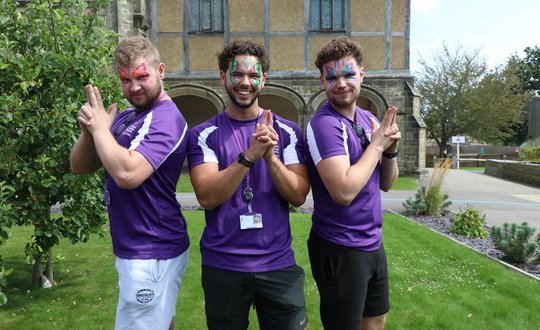 three men with butterfly face paint in charlies angels pose