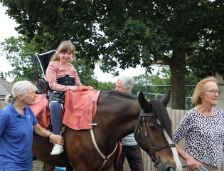 Young girl on the back of a horse smiling.