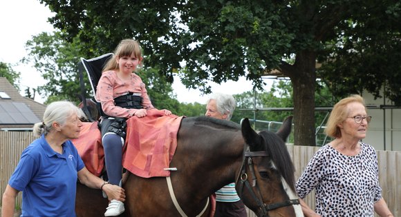 Young girl on the back of a horse smiling.