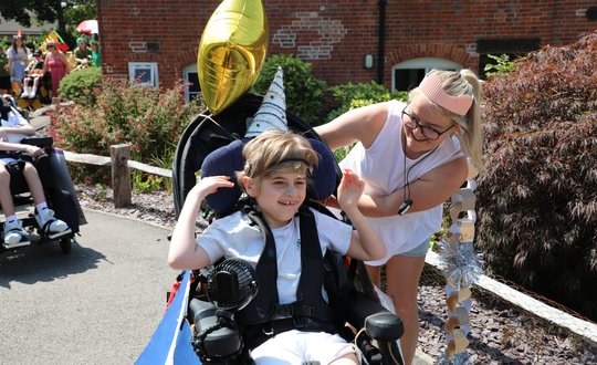 Young boy dressed up smiling with a support worker.