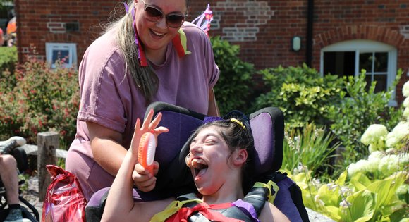 Girl smiling at her support worker dressed colourful.