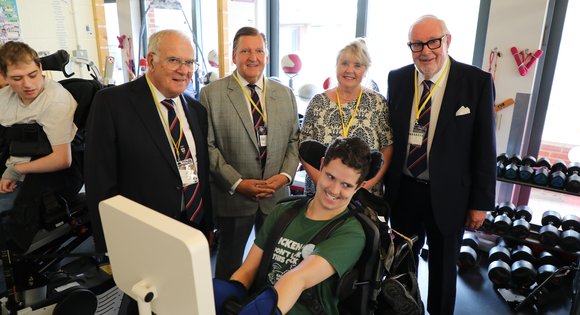 Group of club members crowded by a user using a adaptive gym bike.