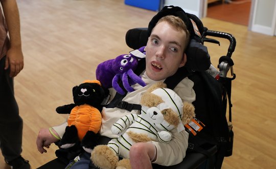 Boy smiling with lots of teddy bear around him.