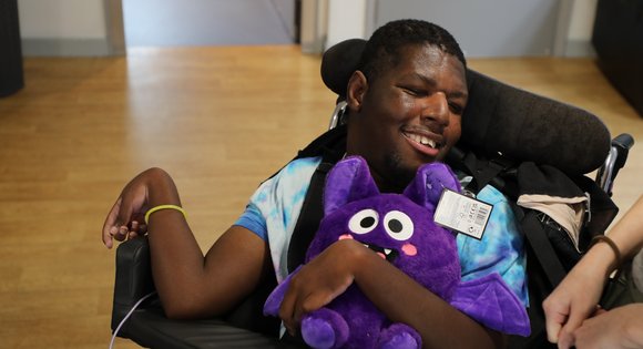 Boy smiling with a purple teddy bear.