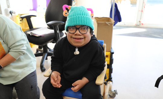 Young boy smiling with a green woolly hat.