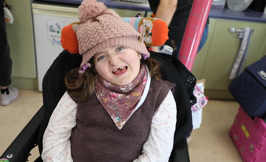 Young girl smiling at the camera with a woolly hat on.