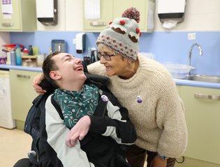Women and boy smiling with woolly hats.