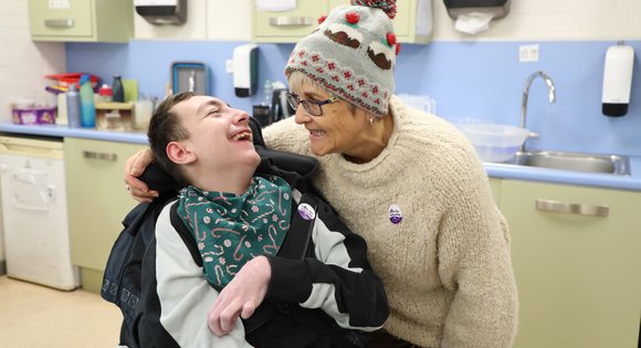 Women and boy smiling with woolly hats.