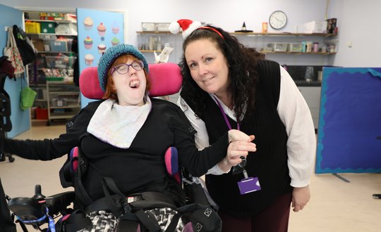 Support worker and young person holdings hands with woolly hats.