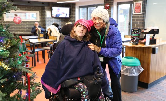 Support worker and young person smiling with a Christmas tree.