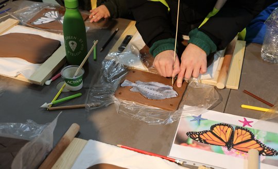Children stenciling animals on clay.