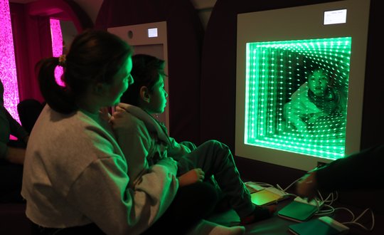 Young boy looking into an infinity mirror.
