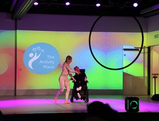 Young girl and carer on a stage dancing.