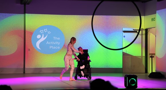 Young girl and carer on a stage dancing.