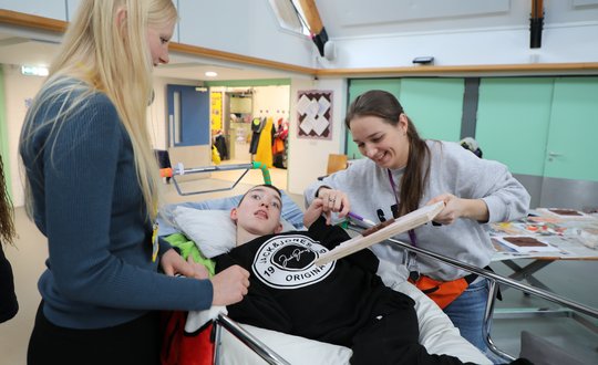 Boy sculpting clay with support worker.