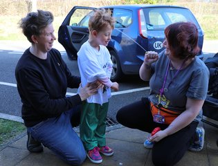 Women squirting water at young boy.