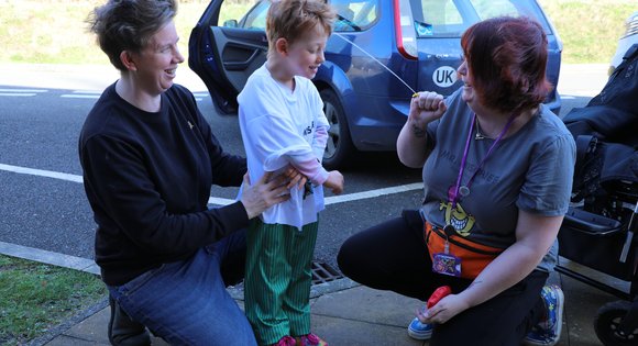 Women squirting water at young boy.