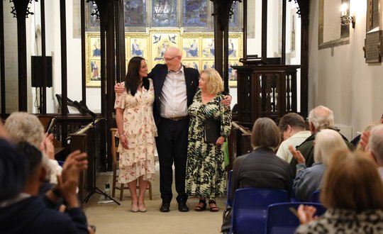 Two women and a man standing at the end of the chapel after singing.
