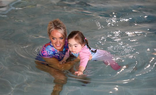 Young girl swimming with help.