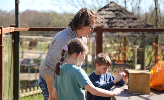 Women and young girl looking at the bug hotel.