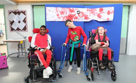 Two boys and a girl smiling with a red nose day painting.