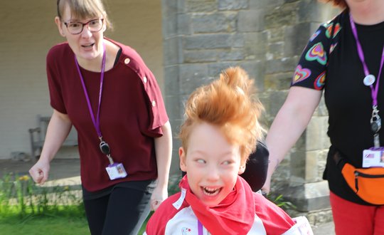 young boy running away from women laughing.