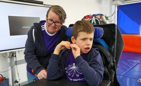 Boy and support worker with purple tops.