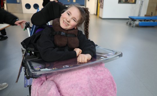 Girl with a plait smiling at the camera.