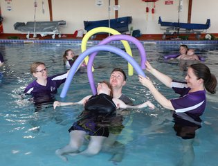Girl floating backwards under an arch of pool floats.