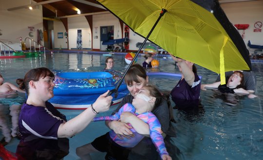 Young girl relaxing in the pool under an umbrella
