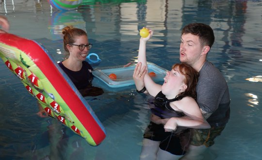 Young girl throwing a ball in the pool.