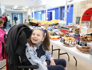 Young girl smiling by lots of cakes.