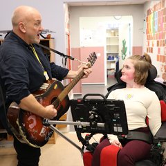 Young person looking at man playing guitar