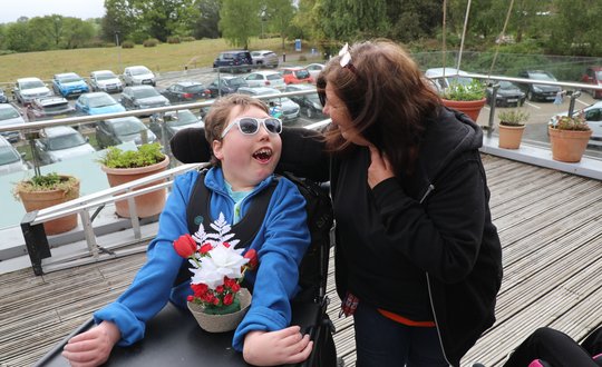 Boy smiling to his support worker with his flower arrangements.