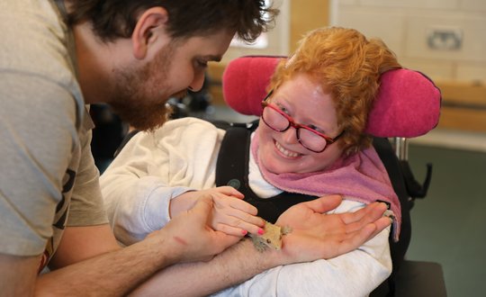 Girl smiling at a man holding a gecko.