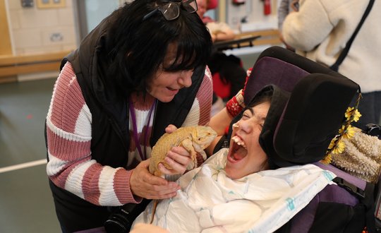 Girl smiling at a bearded dragon.
