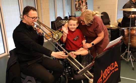 Boy feeling the vibrations from a trumpet.