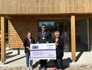 Two women and a man presenting a cheque.
