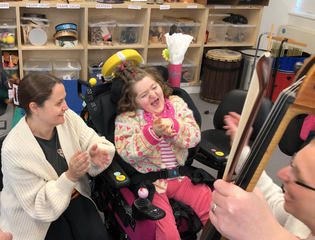 Young girl listening to someone play an instrument.