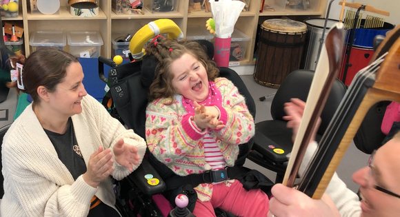 Young girl listening to someone play an instrument.
